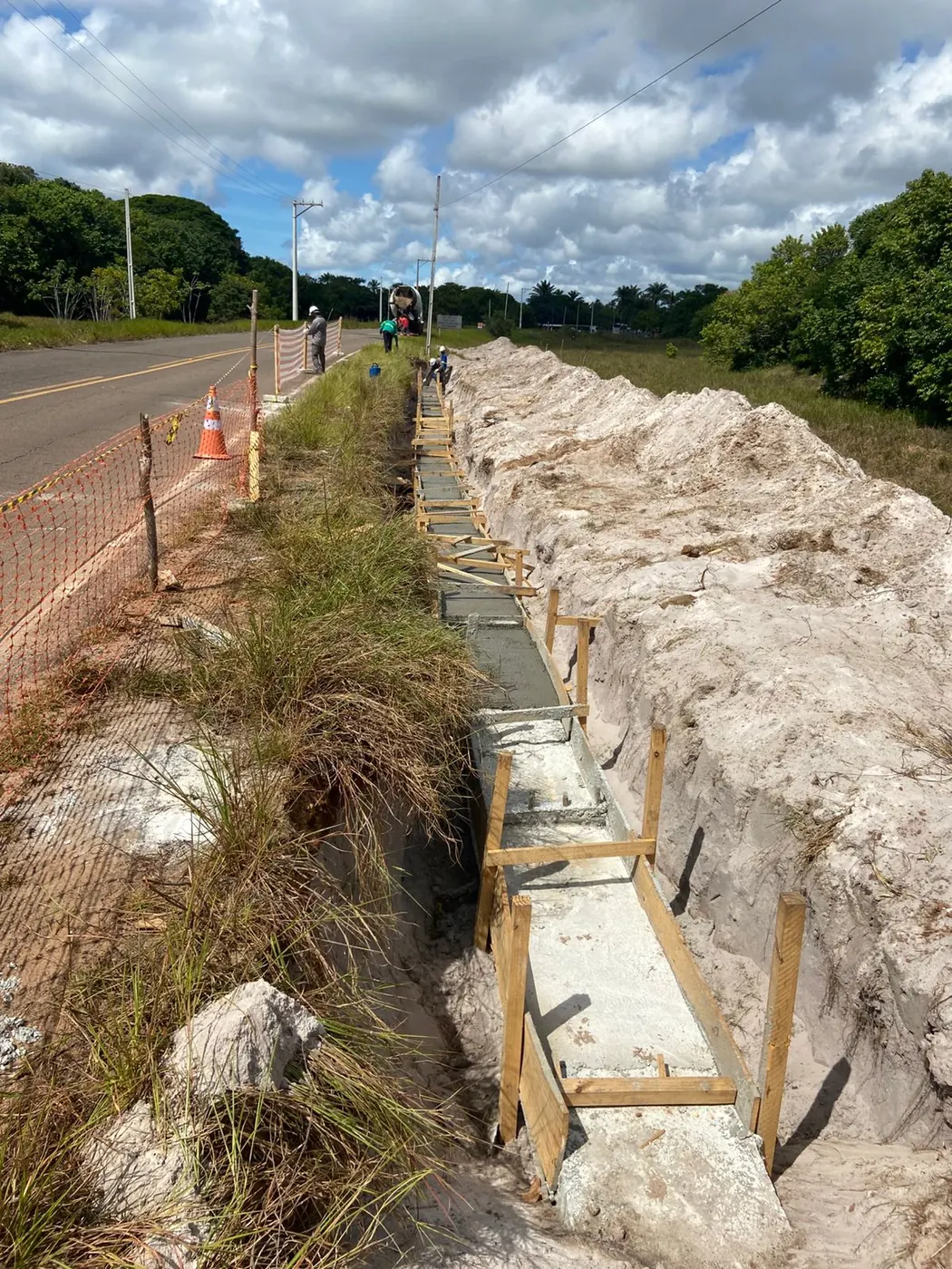 Trecho de vala com formas de concreto às margens da rodovia durante obra de rede