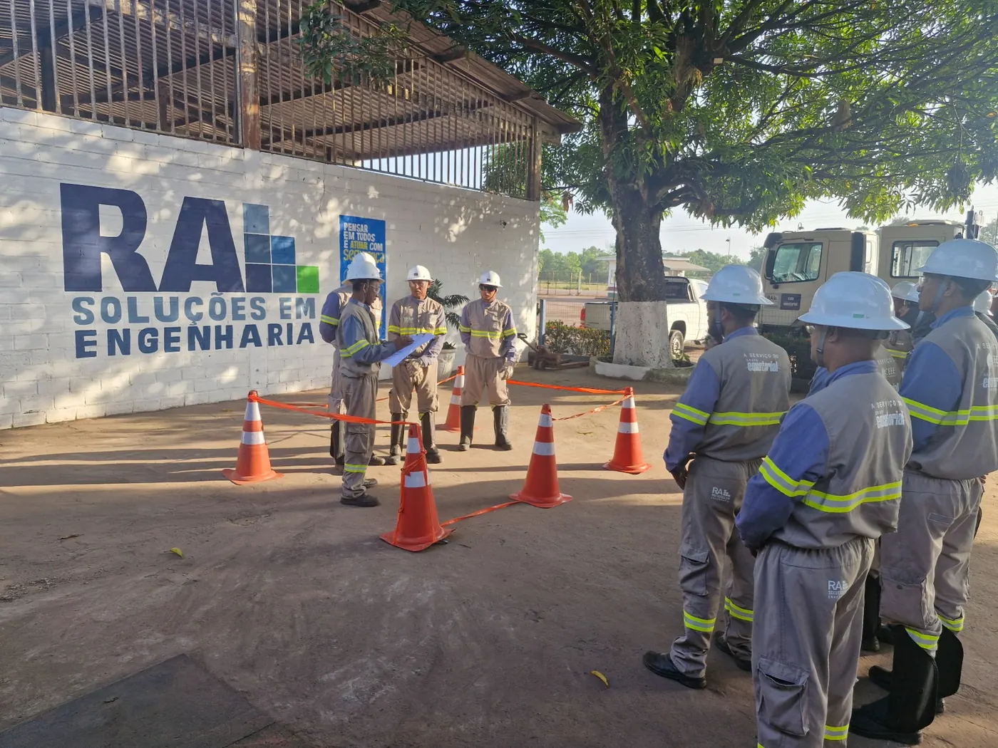 Equipe da RA reunida em diálogo de segurança diante do banner da empresa